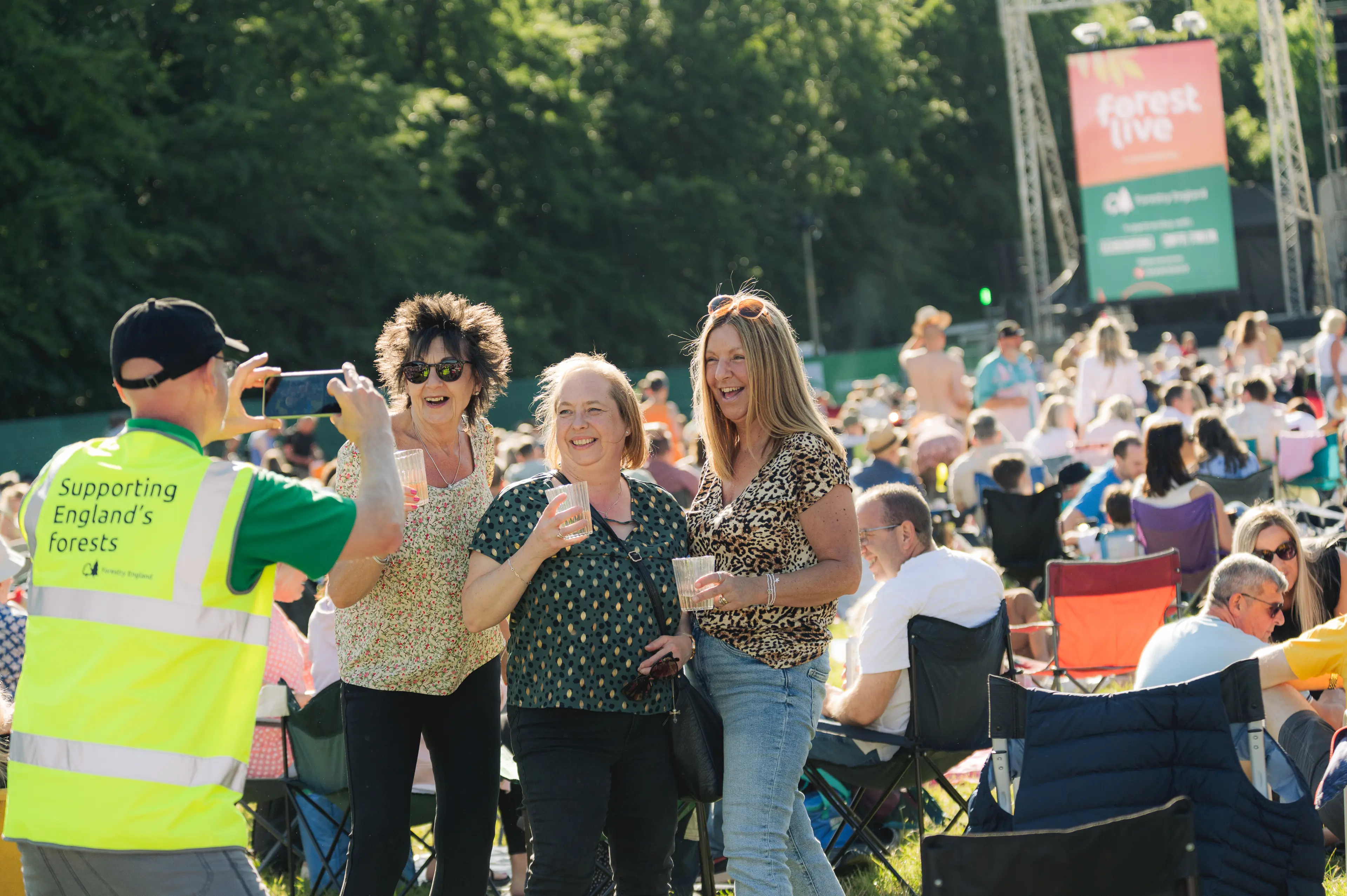 Volunteer taking a photo of three people at Forest Live