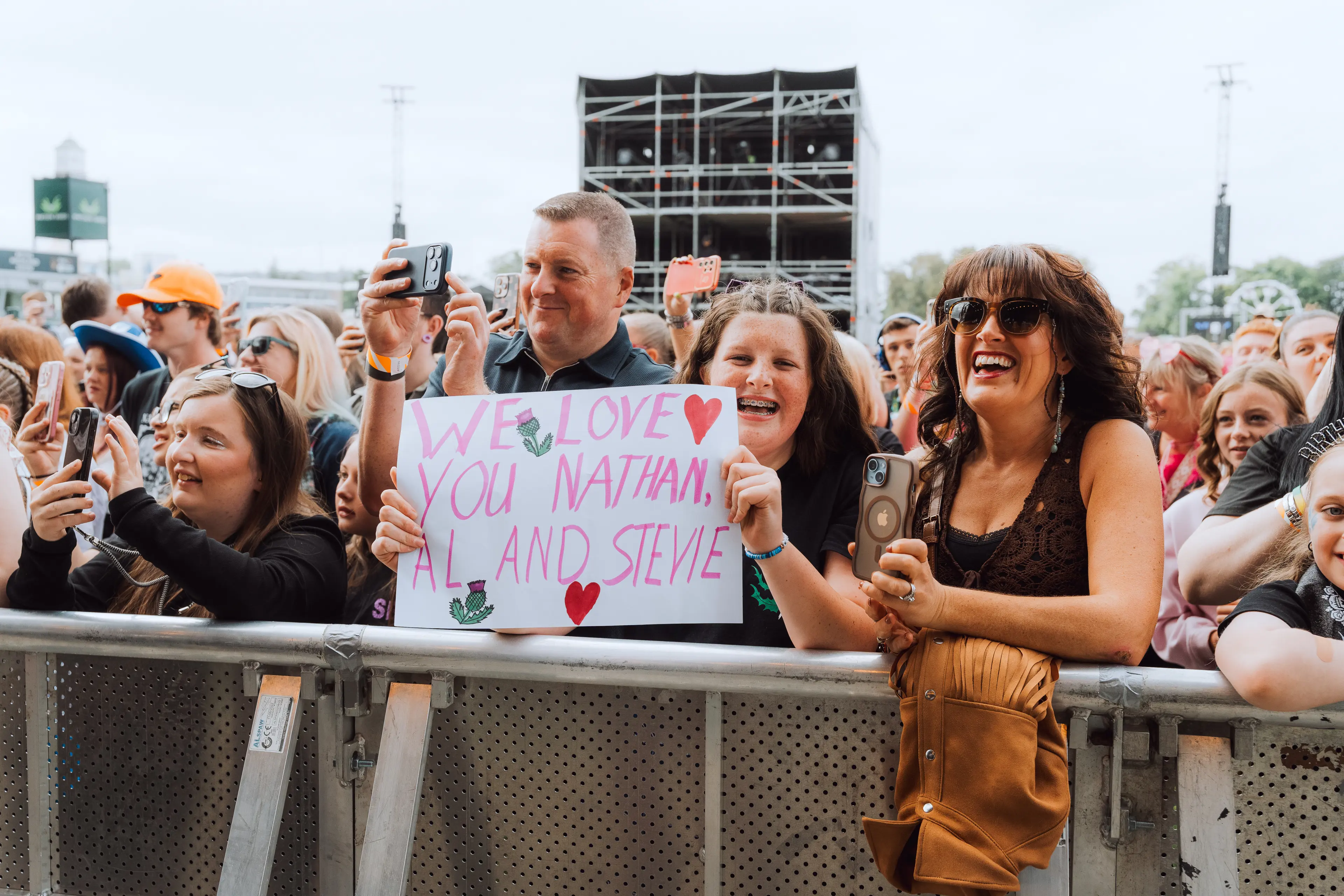Front-row fans hold up a hand-painted sign reading, “We love you Nathan, Al and Stevie.”