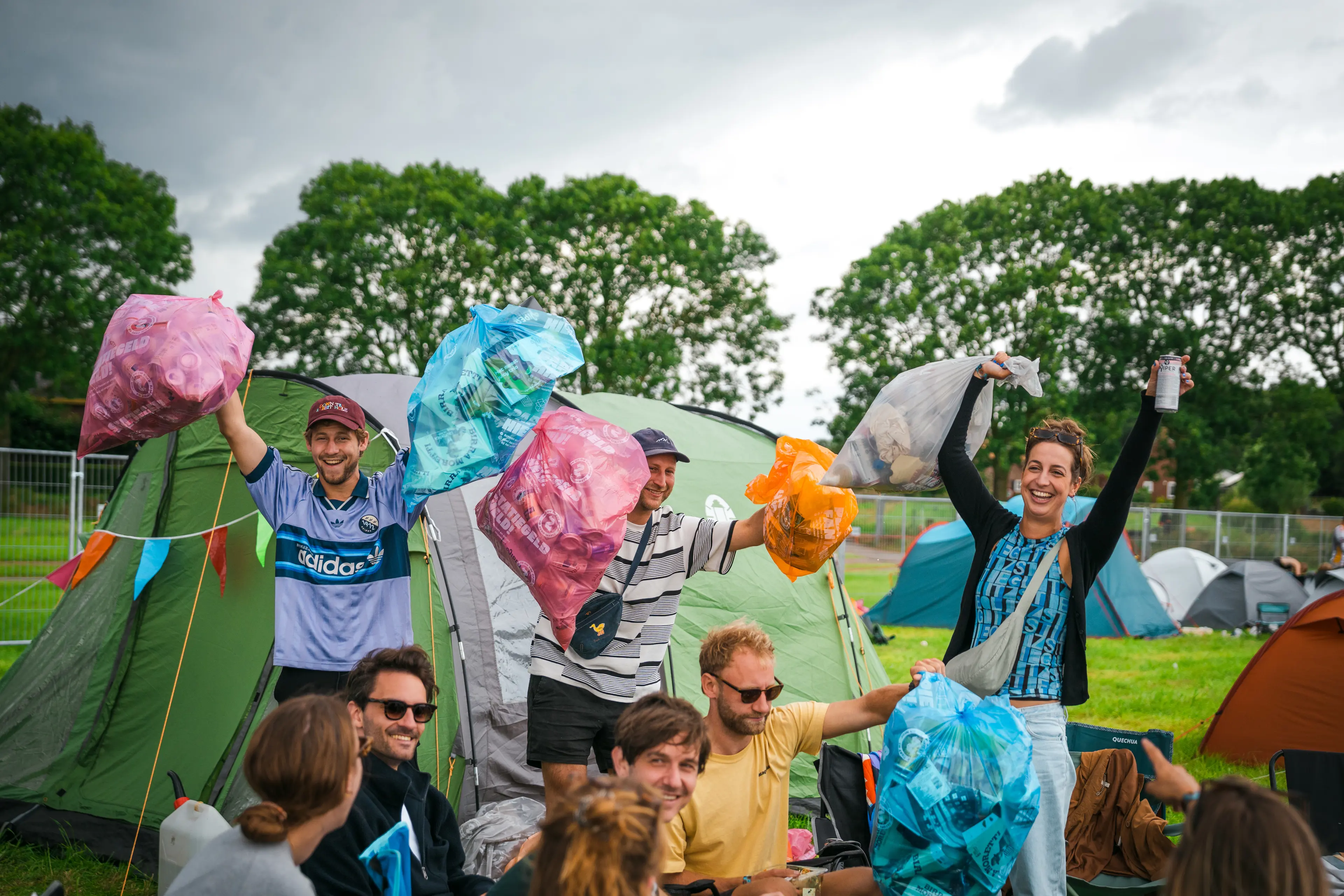 bezoekers met afvalzakken op festival camping