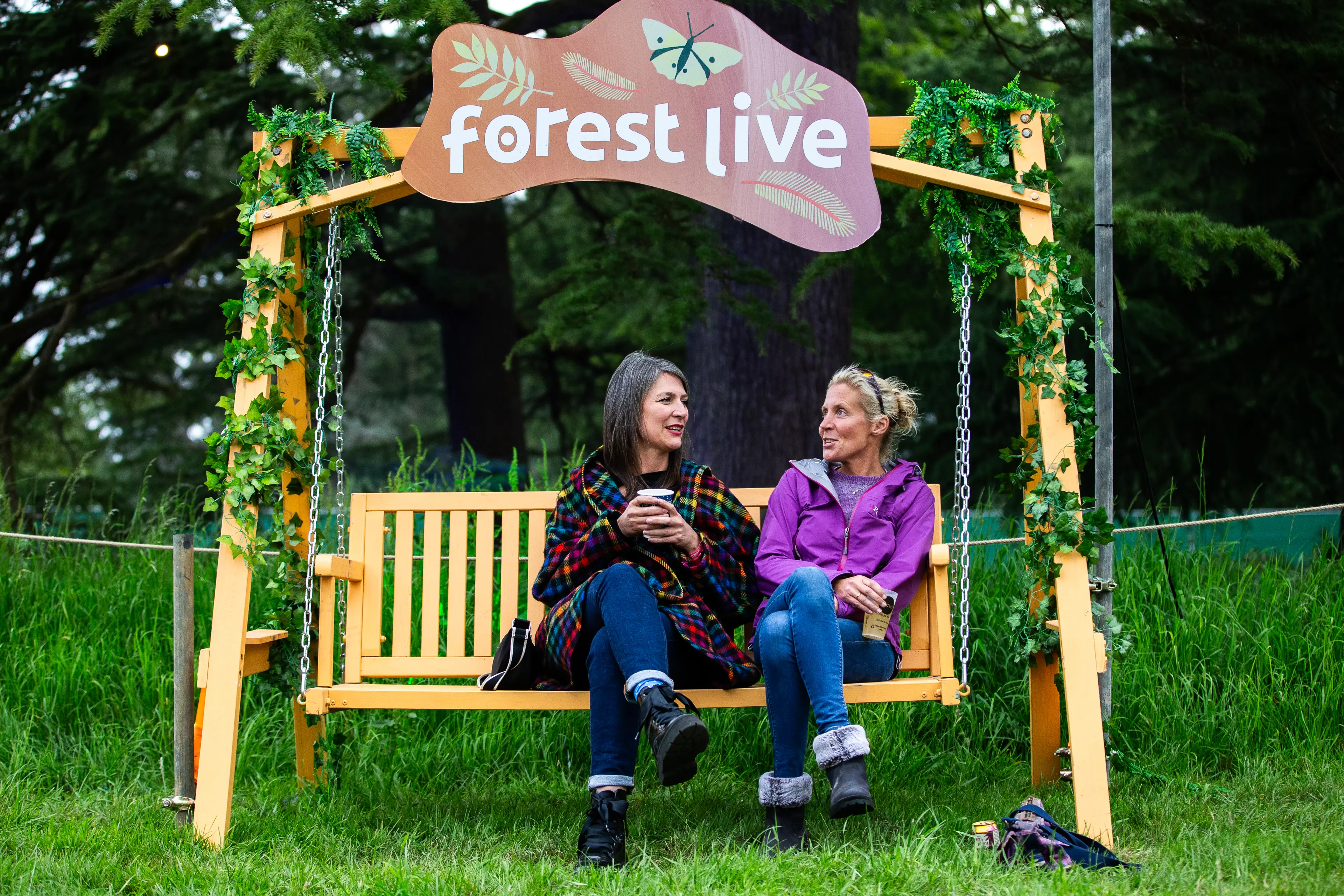 People sat on a bench with a Forest Live sign above it